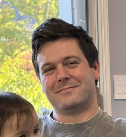 Portrait of Travis Barton smiling indoors.