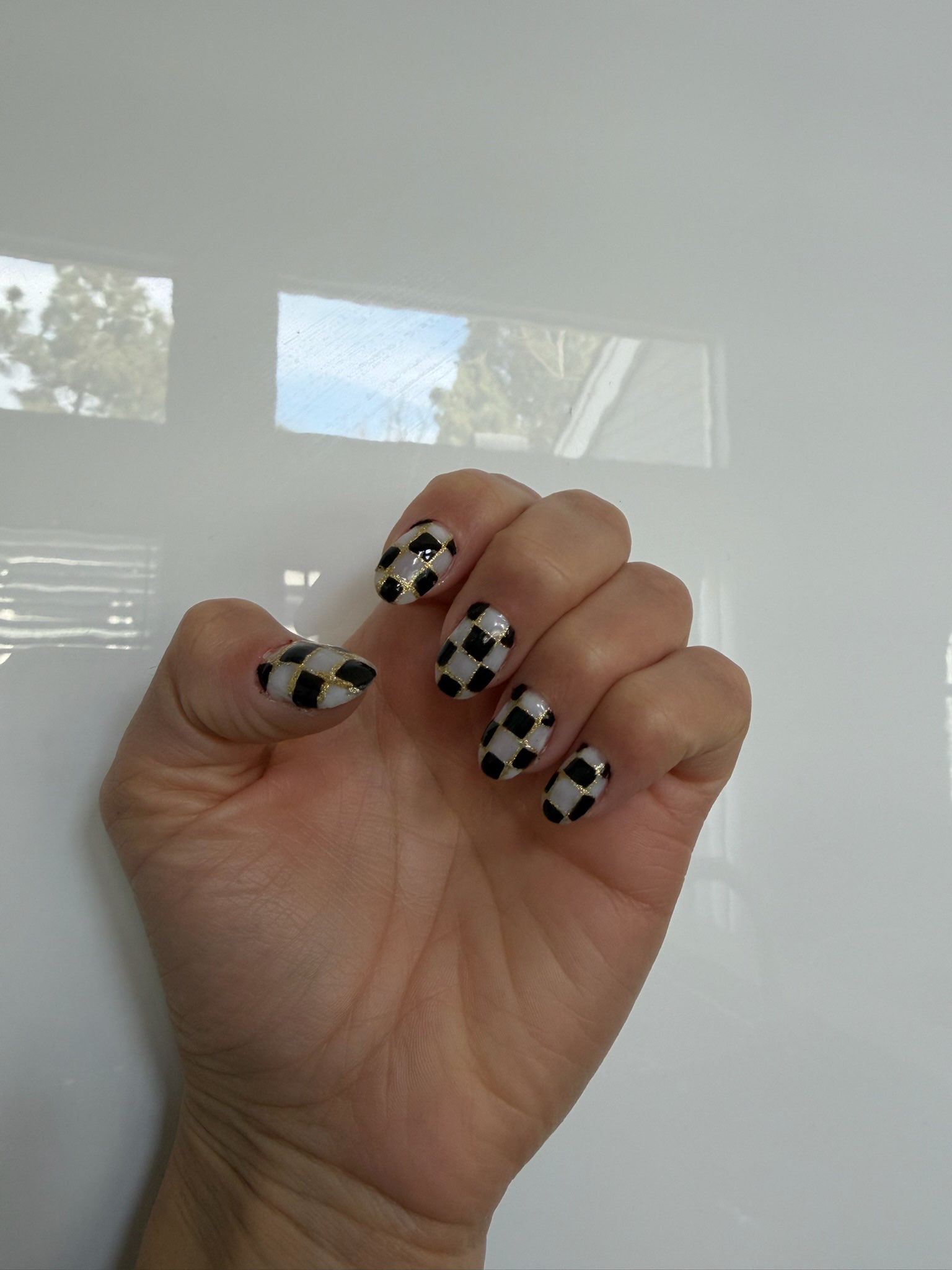 Black and white checkered nails with gold outlines
