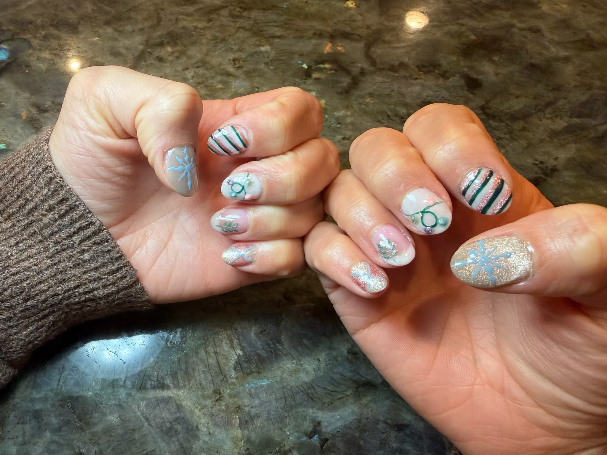 Christmas-themed nails with green stripes and snowflakes