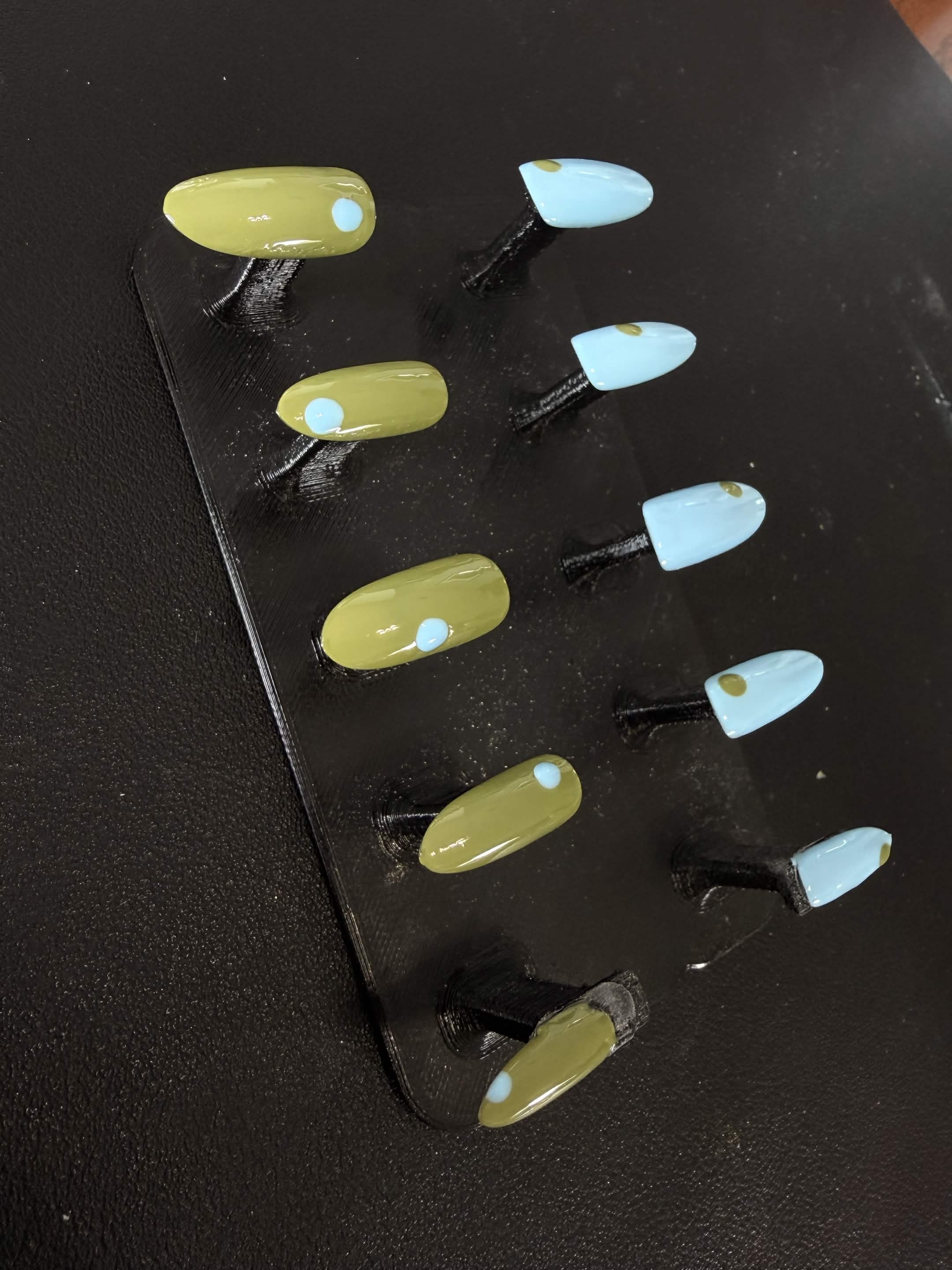 Muted olive and pale blue nails with simple dot accents